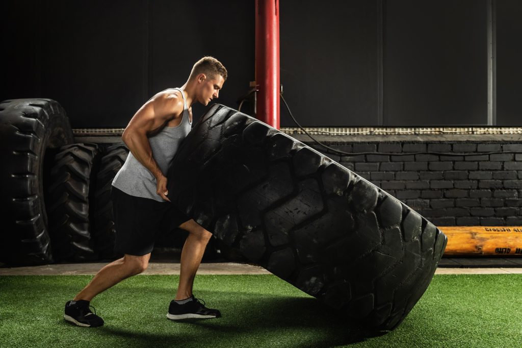 Strong sportsman doing a tire flip exercise